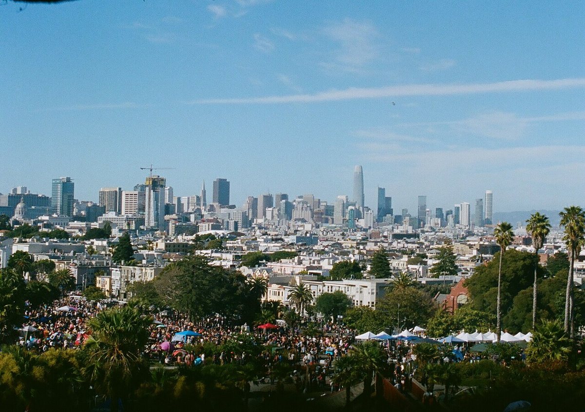 Sunny morning at Dolores Park with picnickers on the grass and the San Francisco skyline in the background